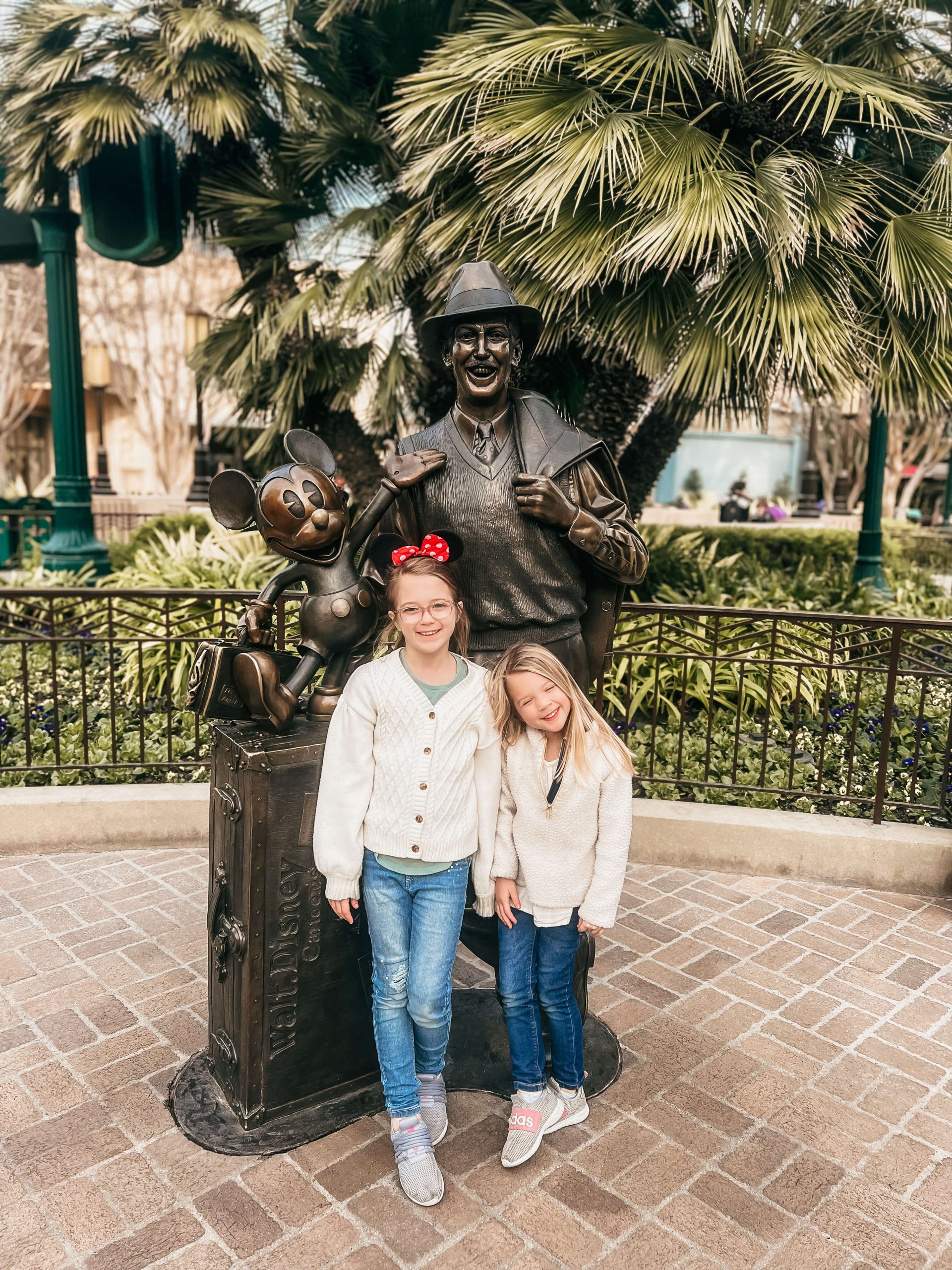 2 little girls in front a walt disney statue