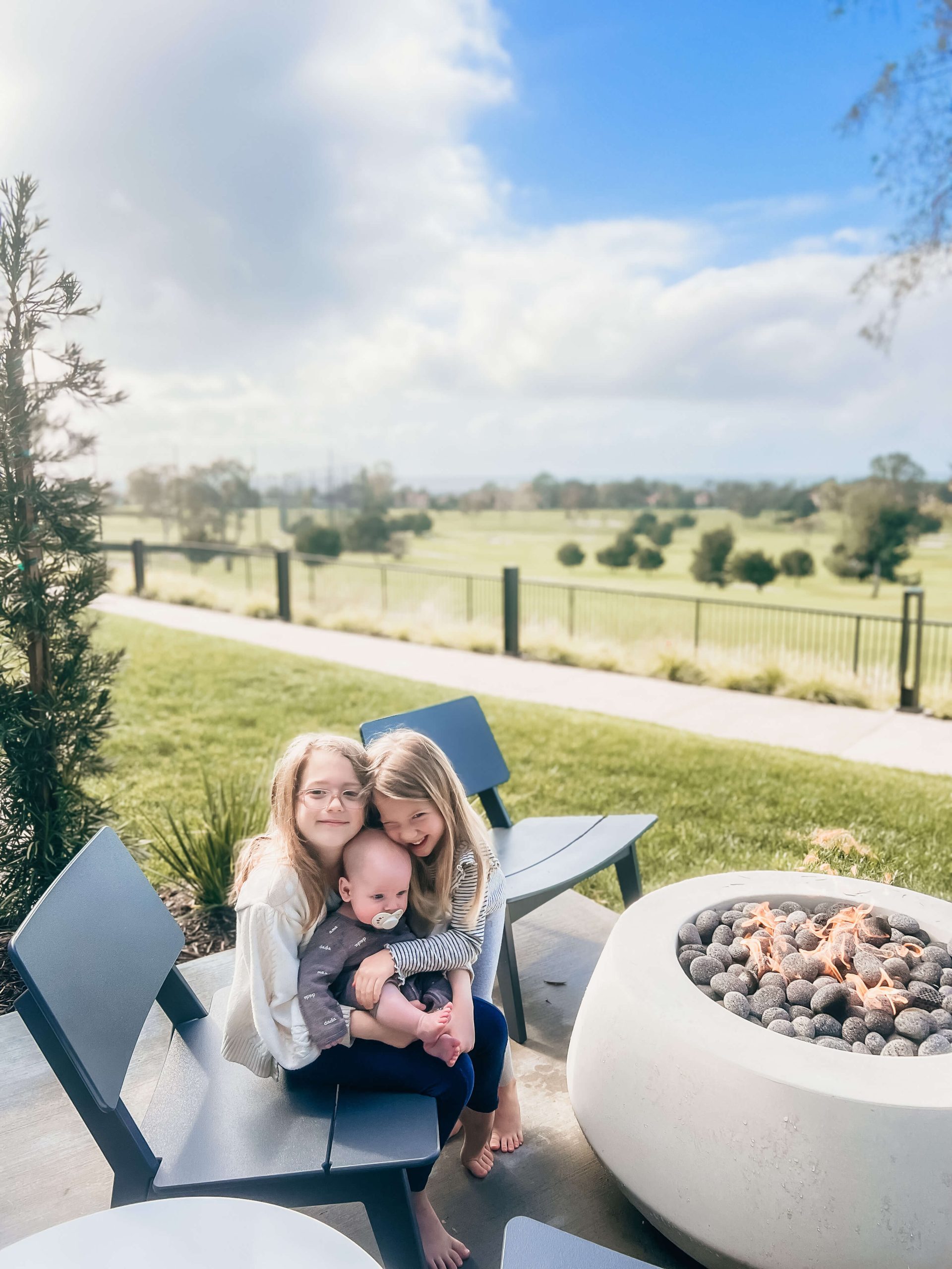 3 kids outside around a fire pit