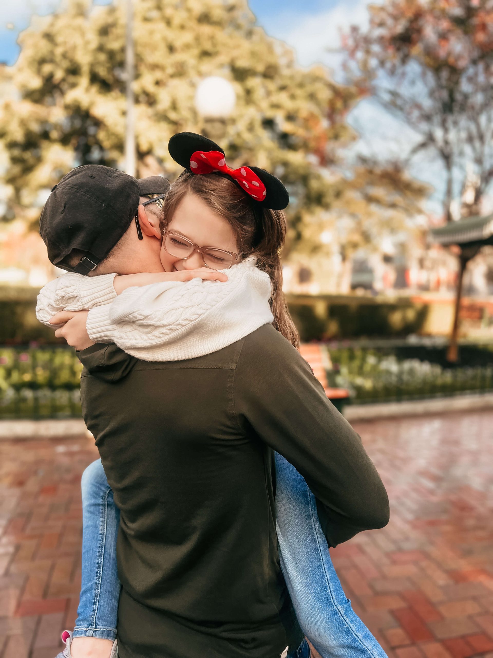 little girl in her dad's arms with Mickey Mouse ears on