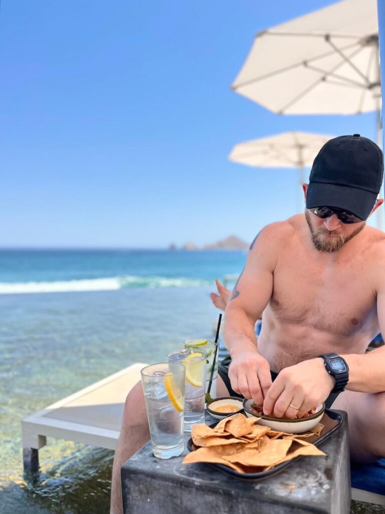 man eating chips and salsa on beach in los cabos