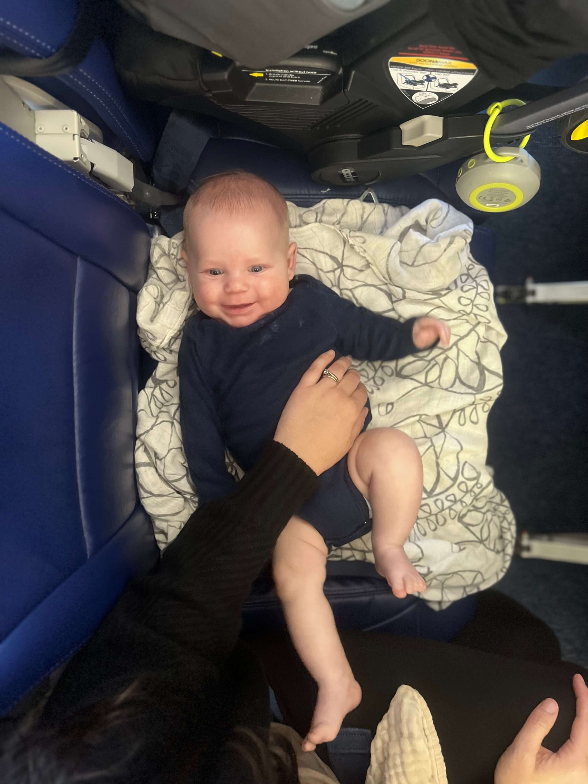 baby boy laying on a blanket in an airplane seat