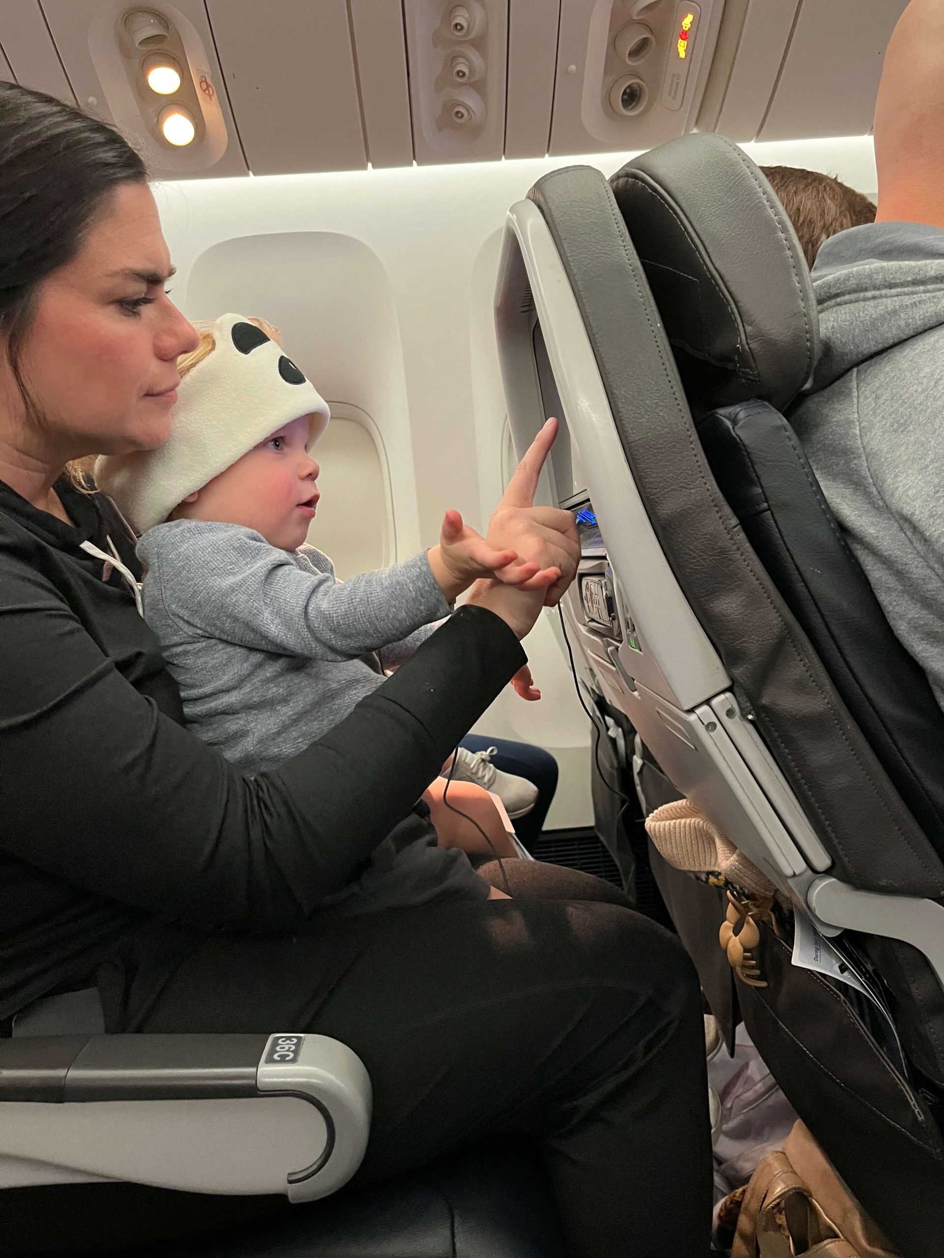 woman sitting in an airplane seat holding an infant on her lap